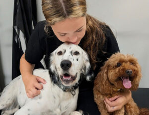 staff petting two happy dogs